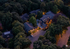 Charming aerial view of a beautifully lit residential complex nestled among lush trees, offering serene and inviting surroundings for peaceful living.