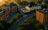 Charming aerial view of a picturesque residential area featuring elegant brick buildings, lush greenery, and a grand colonial-style mansion at sunrise.