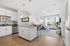 Modern apartment interior showcasing a stylish open-plan kitchen with white cabinetry, a cozy living room with abundant natural light, and contemporary decor.