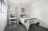 Inviting bedroom with a cozy bed, elegant artwork, and a bright window for natural light.