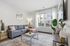 Modern living room with a chic gray sofa, stylish floor lamp, and large window showcasing urban views.