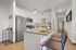 Modern kitchen with sleek white cabinetry, stainless steel appliances, and a stylish island featuring contemporary pendant lighting and bar seating.