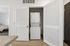 Modern apartment laundry closet featuring an efficient stacked washer and dryer set, adjacent to a cozy bedroom space.