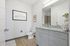 Elegant bathroom with modern gray vanity, sleek sink, stylish artwork, and warm wood flooring.