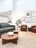 Bright and modern living room featuring a sleek sofa, elegant coffee tables, stylish armchairs, and contemporary wall art for a welcoming atmosphere.