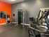 A fitness center at The Villas of Castleton featuring exercise equipment and vibrant orange walls.