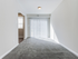 Empty room at Catons Villas South with gray carpet, white walls, sliding glass doors, and soft natural light.