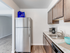 Modern kitchen at Catons Villas South with stainless fridge, wooden cabinets, marble countertop, blue bowl, and coffee maker.