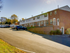 Row of red-brick townhouses at Catons Villas South under blue sky, with parked cars, trees, and serene suburban feel.