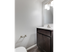 Small bathroom at Catons Villas South with light gray walls, dark wood vanity, toilet, and mirror with overhead lights.