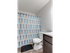 Small bathroom at Catons Villas South with gray walls, blue-white checkered shower curtain, white toilet, dark wood vanity, and black mat.