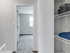 Minimalist interior at Catons Villas South with closet, blue blanket, basket, and open door to bright carpeted room with window.