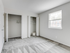 Empty room at Catons Villas South with light gray walls and carpet, two open closets, and a window letting in natural light.