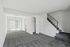 Bright empty room at Catons Villas South with gray carpet, white walls, staircase, sliding glass door, and open closet.