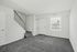Bright modern living room at Catons Villas South with cream sectional, gray carpet, large TV, and staircase with black railing.