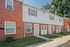 Row of modern brick townhouses at Catons Villas South with white doors and windows, green lawns, and clear sky.