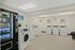 Bright laundry room at Catons Villas South with vending machine, white washers and dryers, clock, and decorative prints above.