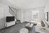 Bright living room at Catons Villas South with gray carpet, white sectional sofa, TV, coffee table, and large window.