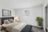 Minimalist bedroom at Catons Villas South with large bed, striped pillows, beige blanket, bedside lamp, potted plant, and window.
