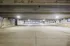 A spacious, brightly lit parking garage at Lofts at Yard 56 with empty parking spaces and illuminated overhead lights.