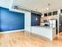 Stylish open kitchen in Lancaster Lofts with vibrant blue walls and rich hardwood floors, creating a welcoming space.