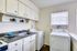 Bright kitchen with a compact laundry area and machine, featuring elegant cabinetry and modern appliances.