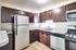 Contemporary kitchen showcasing stainless steel appliances paired with rich wood cabinets at Allyson Gardens Apartments.