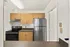 Modern kitchen featuring stainless steel appliances and sleek wooden cabinetry that leading into the hallway and dining room of the apartment.