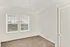 A bright, sun-filled room featuring a spacious window that lets in natural light, soft, plush carpeting, and a convenient closet with sleek doors for added storage.