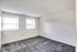 A bright, empty bedroom in Bright Meadows Townhomes featuring two windows and soft carpeting.