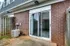 A cozy brick patio at Bright Meadows Townhomes featuring a sliding glass door and a surrounding fence.