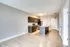 A sleek modern kitchen with dark cabinetry and an open-plan design in a bright apartment.