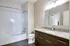 A bright contemporary bathroom with a sleek granite countertop, elegant cabinetry, and a spacious bathtub.