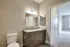 A contemporary bathroom with a stylish vanity, mirrors, and a view into a carpeted bedroom.