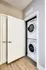 A laundry unit with a stacked washer and dryer in a modern apartment.