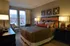A cozy bedroom with chic decor, featuring a plush bed, stylish lamps and stunning city views.