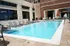 A welcoming outdoor pool area at a modern apartment complex, featuring lounge chairs and umbrellas.