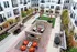 A lively courtyard with contemporary seating, lush greenery, and a chic outdoor area, framed by luxury apartment buildings.