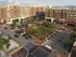 An aerial view of a lively urban community, with modern brick buildings encircling a lush green park square.