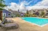 A serene pool at Hampton Point Apartments surrounded by lush greenery and inviting lounge areas.