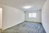 An inviting empty room in Allyson Gardens Apartments, showcasing a cozy carpet and fresh white walls.