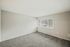 Modern room with neutral walls, plush carpeting, and large window offering ample natural light.