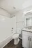 Bright, modern bathroom featuring a bathtub, tiled walls, sleek vanity with a granite countertop, and wood flooring.