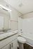 Elegant bathroom with modern granite countertop, sleek fixtures, and a tiled bathtub.
