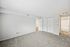 Spacious bedroom with plush carpeting, white walls, and large closet space, leading to a bathroom.