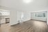 Bright open living area with hardwood floors, large window, and view of modern kitchen.