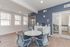 Modern office area featuring a round table with chairs, natural light from large windows, and a sleek blue accent wall.