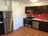 A sleek kitchen with contemporary dark cabinets, stainless steel appliances, and elegant wooden flooring for a stylish, modern feel.