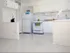 A contemporary white kitchen at Greenbriar Estates featuring white cabinets, a fridge, stove, and minimalist decor for a clean, sleek look.