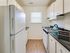 A charming kitchen at Sequoia Manor Apartments with sleek a white cabinetry, black marble, a spacious refrigerator, and an abundance of natural light for a bright, inviting atmosphere.